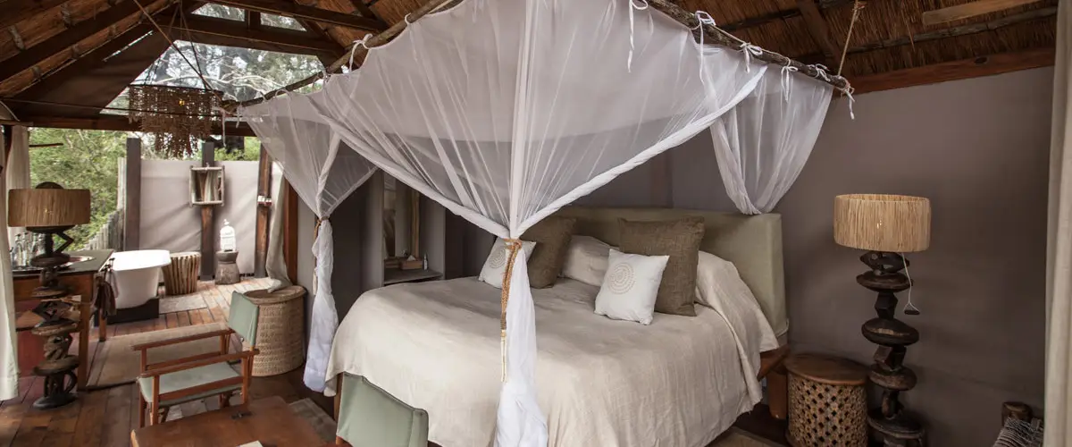 Opulent thatched safari suite with open-air bathroom.