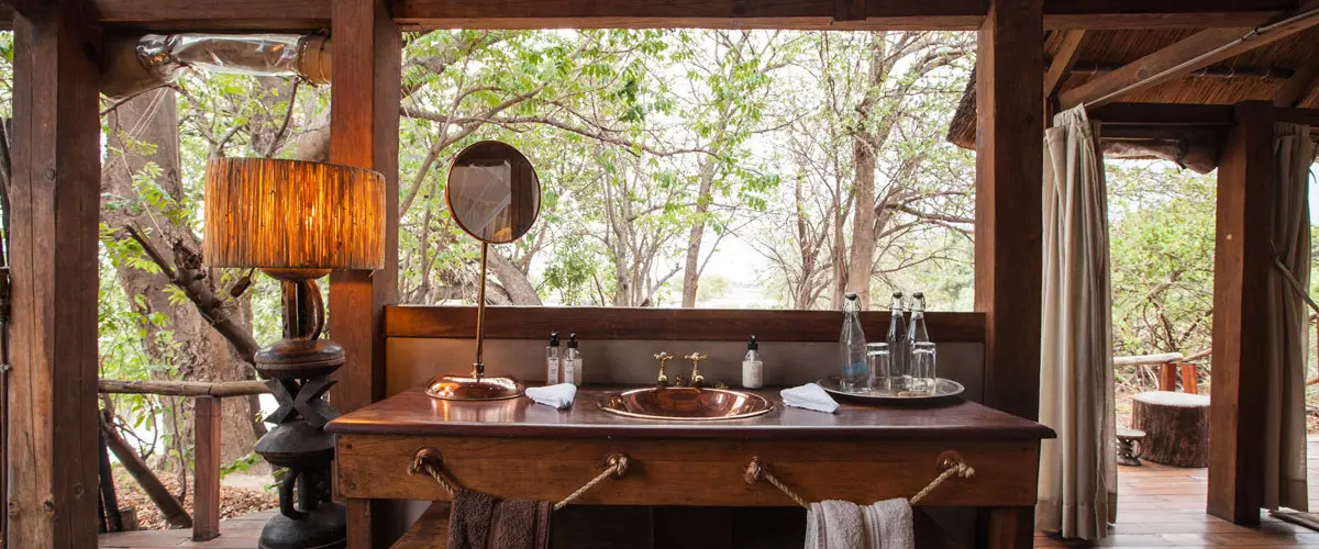 Spacious wooden bathroom vanity with panoramic bush views at Sindabezi Island Lodge.