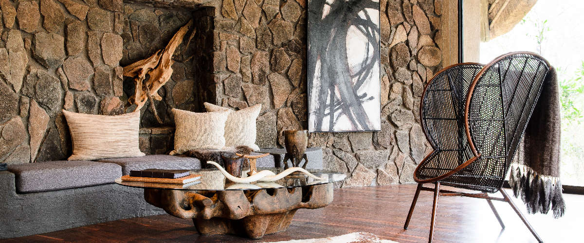 Elegant lodge lounge with organic stone and African art décor.