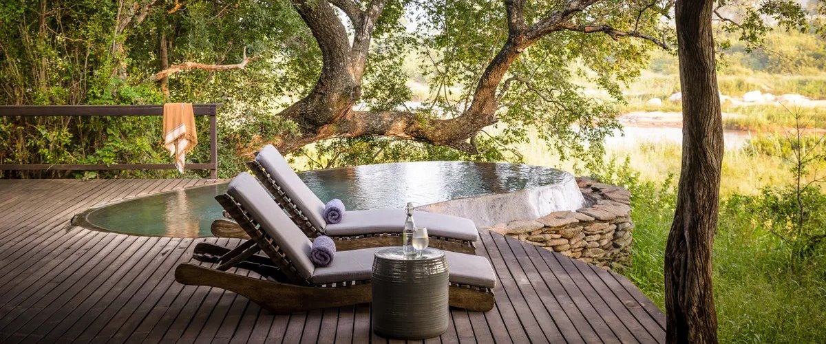 Open-air deck with private plunge pool and two sun loungers shaded by tree..