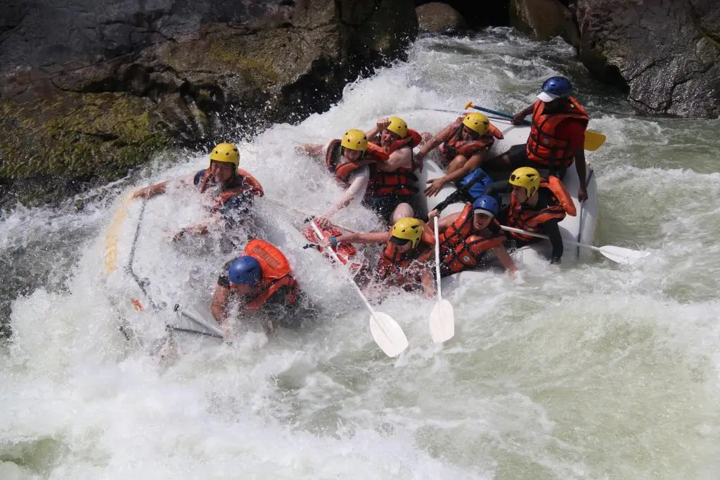 Helmeted rowers crashing a raft through the white water rapids of the Zambezi River