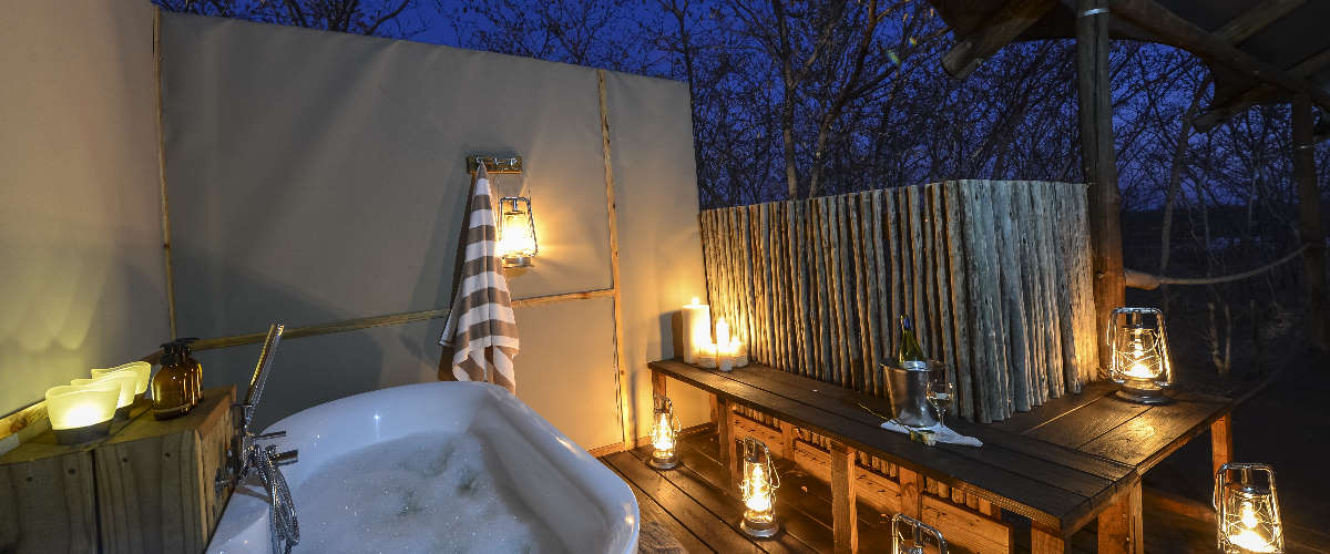 Romantic lantern-lit wooden deck with outdoor bath tub at Toka Leya Lodge.