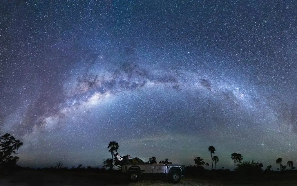 night drive safari guests in vehicle under a glowing milky way at Tubu Tree Camp in Okavango Delta