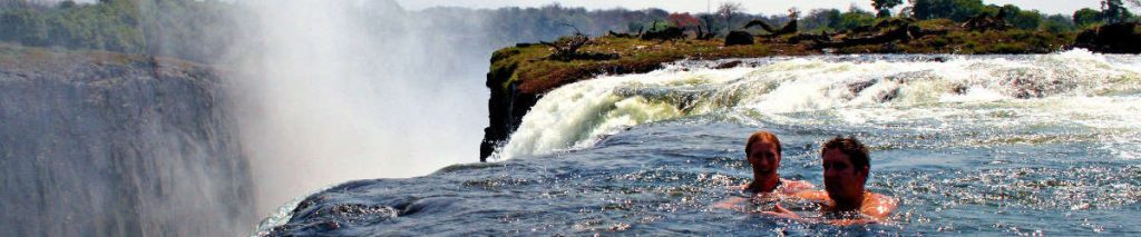 Two people swimming in Devil's Pool on the edge of Victoria Falls.