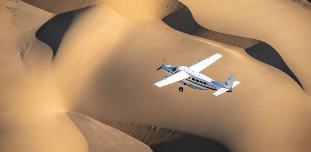 Wilderness Air small plane flying across Namib Desert dunes